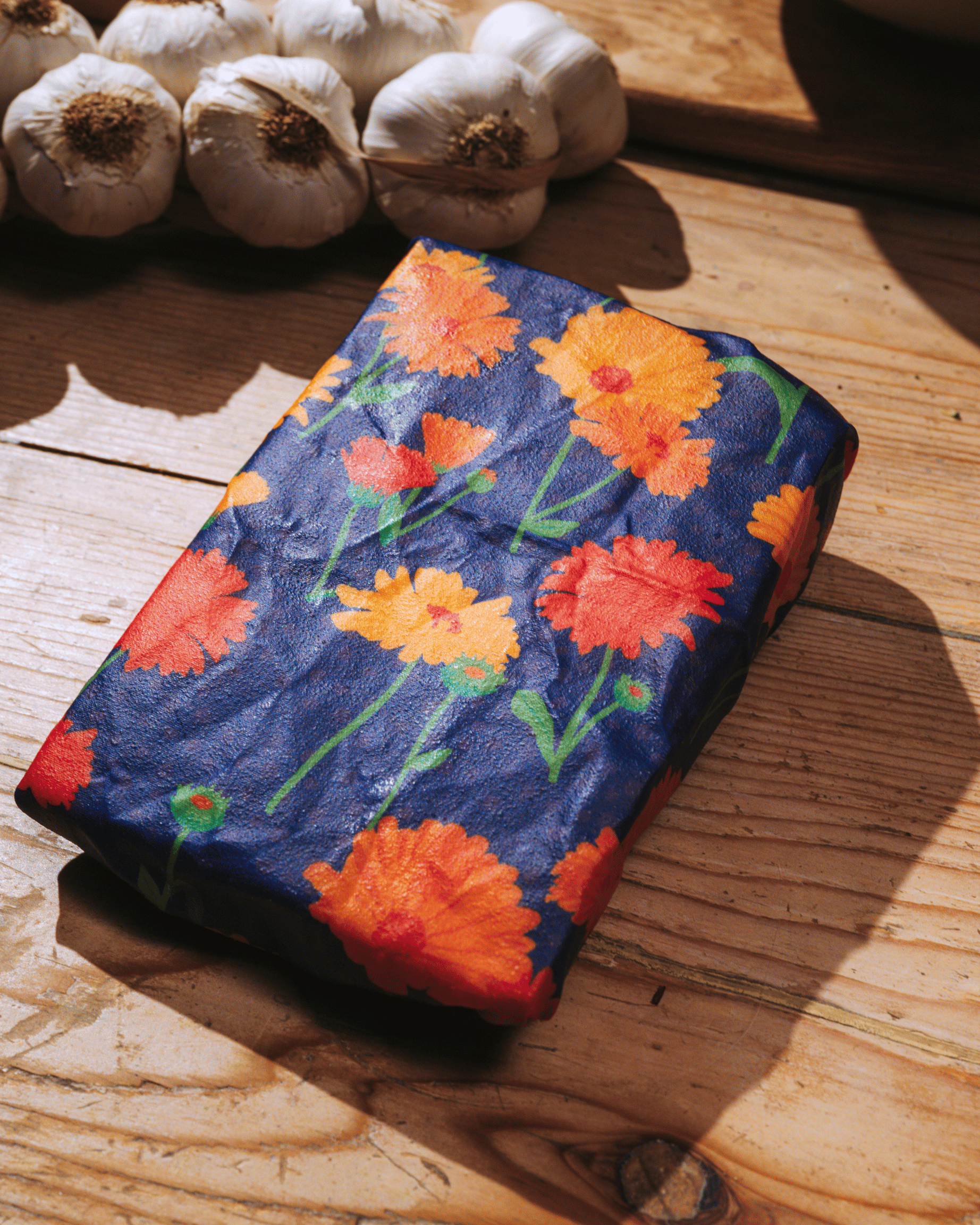 En bivaxduk med motiv av ringblomma i på ett bord.