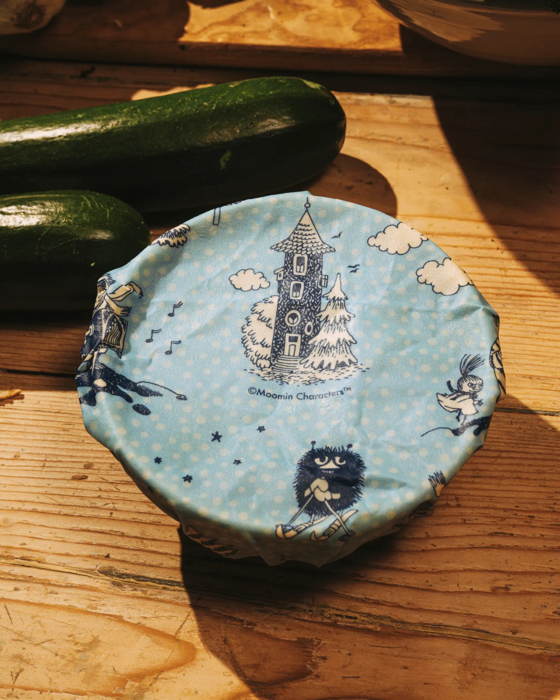 EN bivoksark med Mummi motiv over en bolle ved siden av et par agurker.