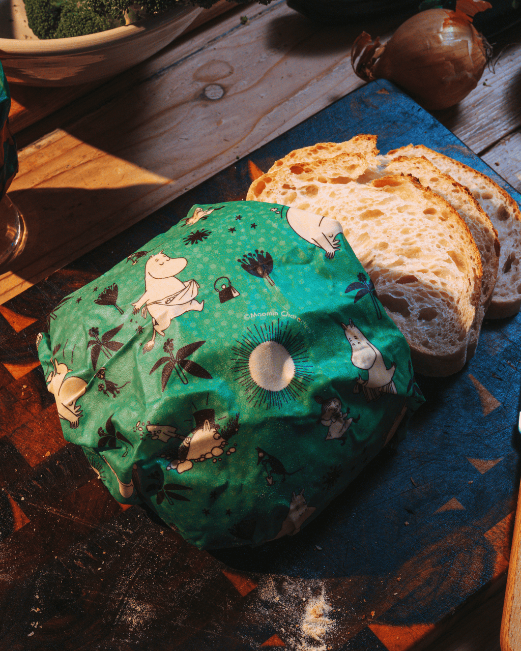 Bivaxduk med mumin motiv på ett bord med bröd och en lök
