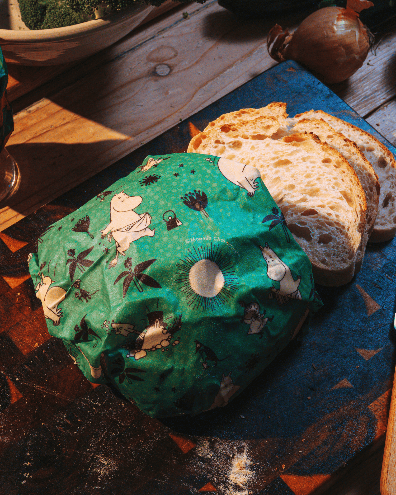 Bivaxduk med mumin motiv på ett bord med bröd och en lök
