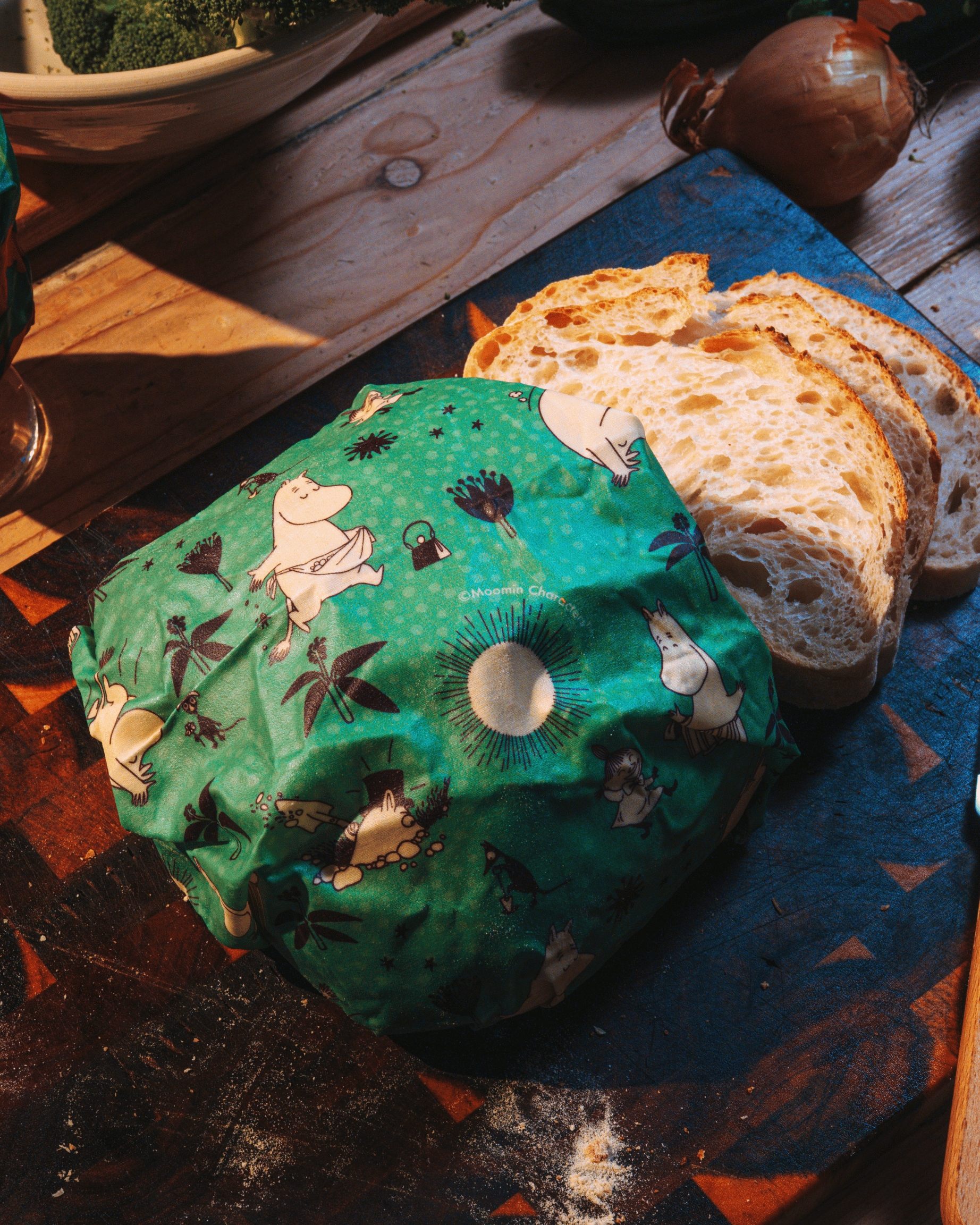 Bivaxduk med mumin motiv på ett bord med bröd och en lök