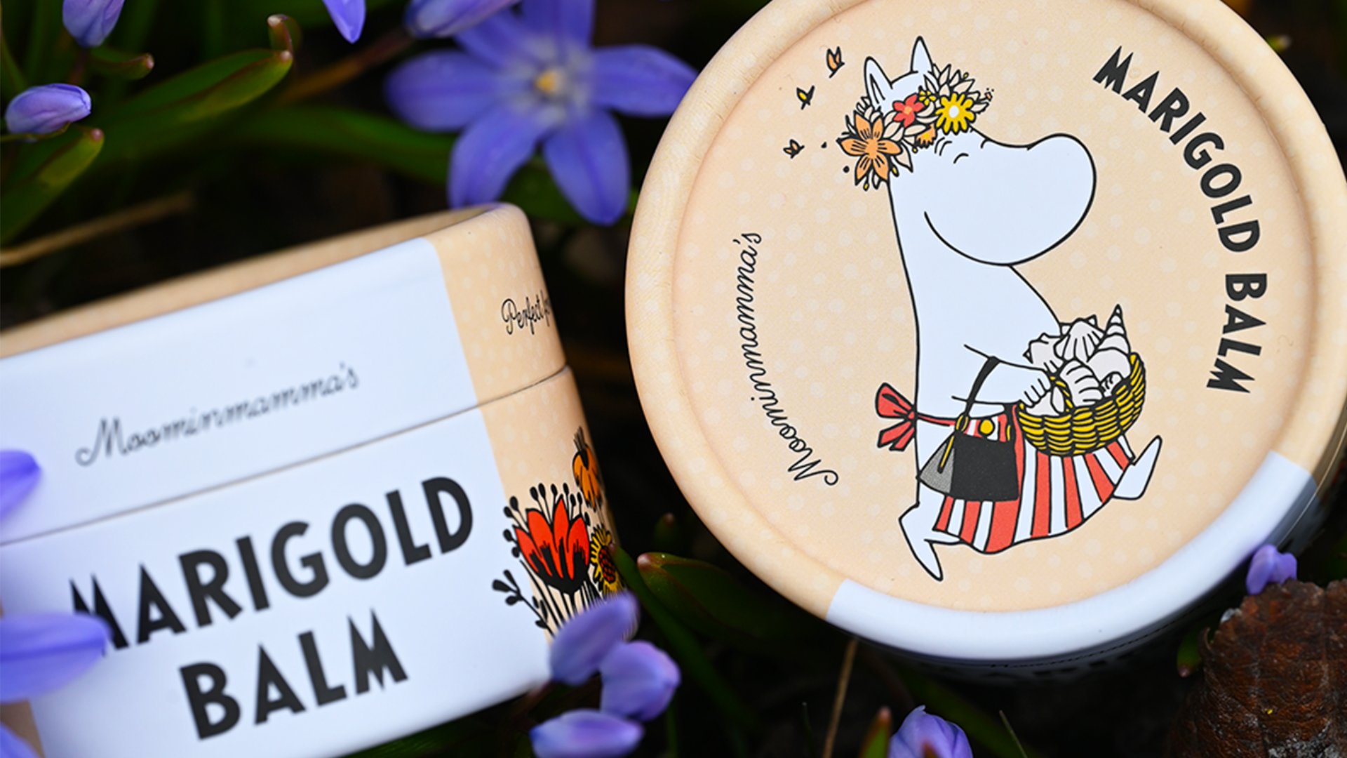 Ett marigold balm med moomin tema som ligger bland lila blommor