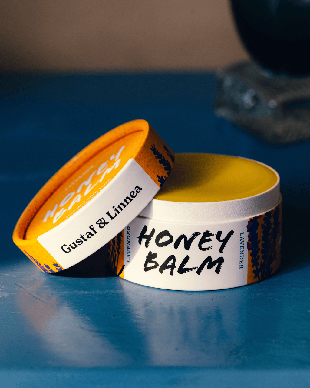 An open jar of honey ointment on a blue table.