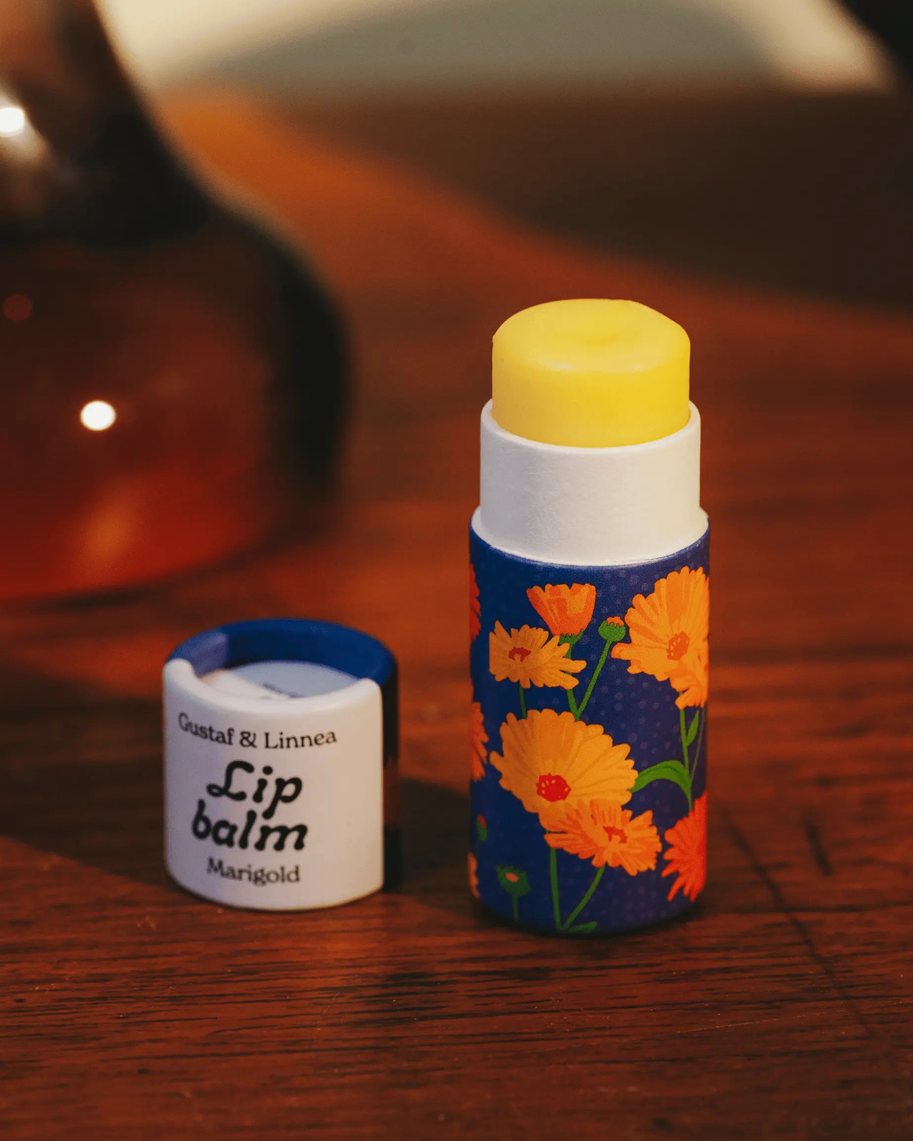 En åpnet leppepomade med smaken av ringblomst på et bord.