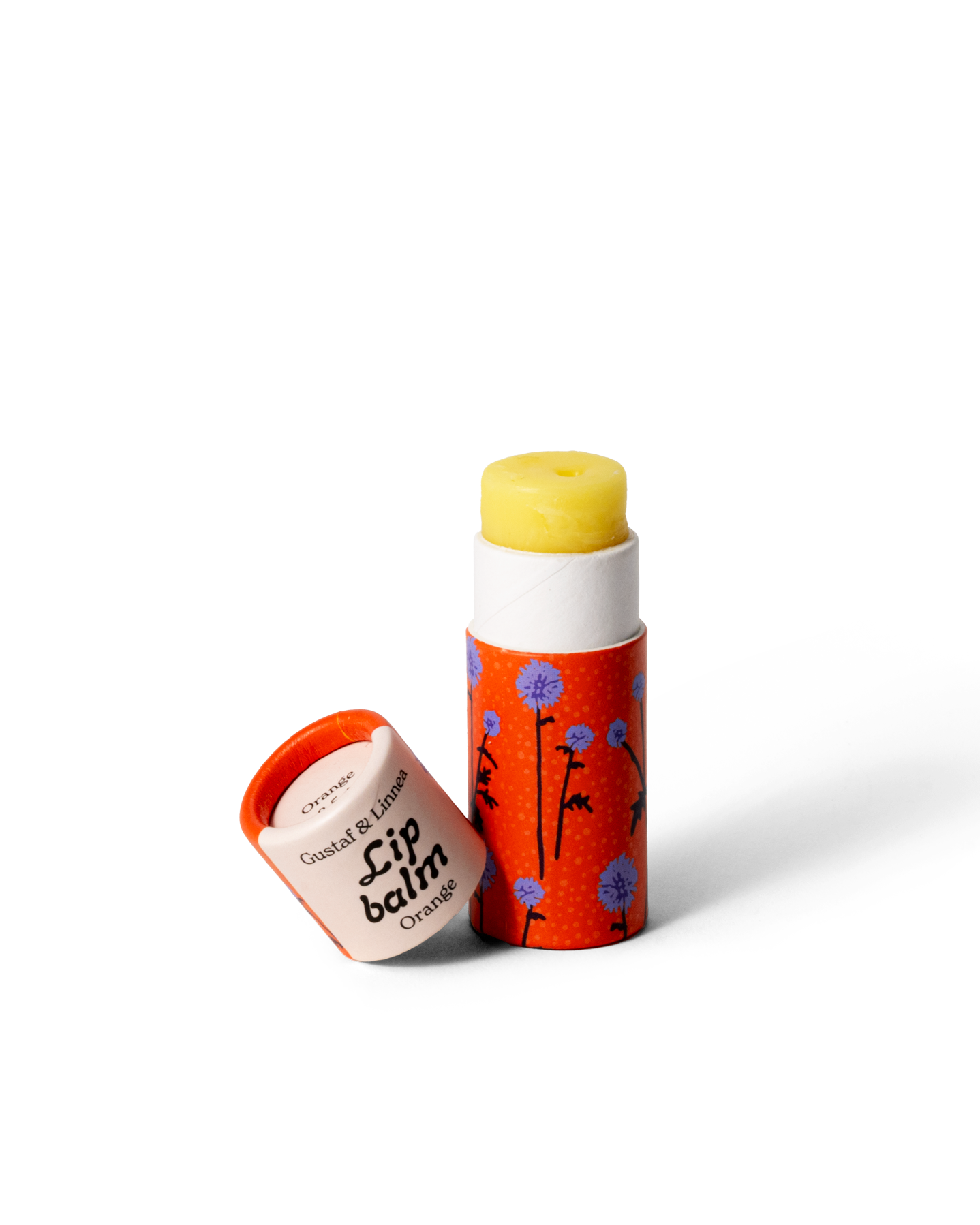 Läppcerat med smak av apelsin, öppnad hylsa med gult cerat och mönster av bolltistlar.