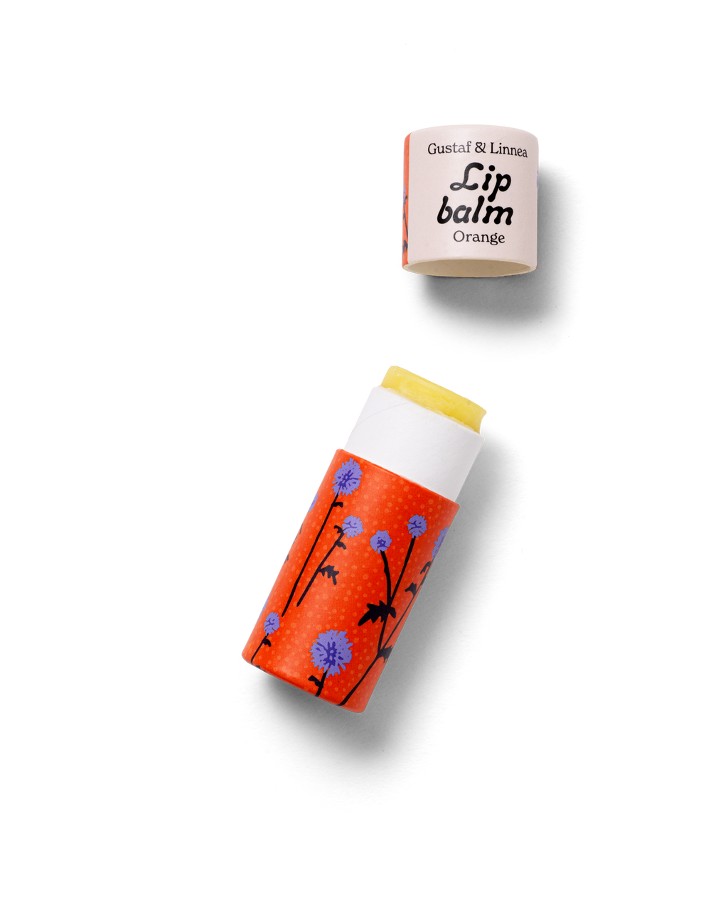 Handmade lip balm with thistle pattern, shown open with lid on the side.